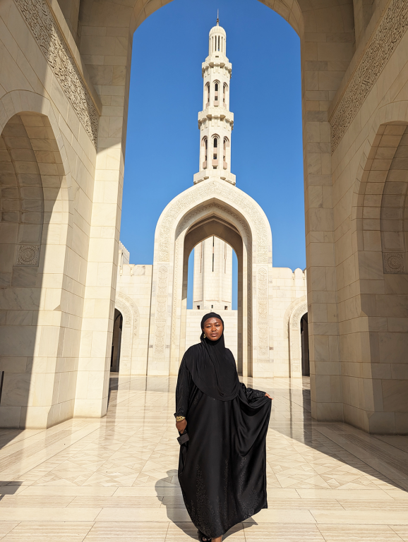 Jadesola, wearing a black robe, stands gracefully in front of Sultan Qaboos mosque in Muscat during a visit to Oman
